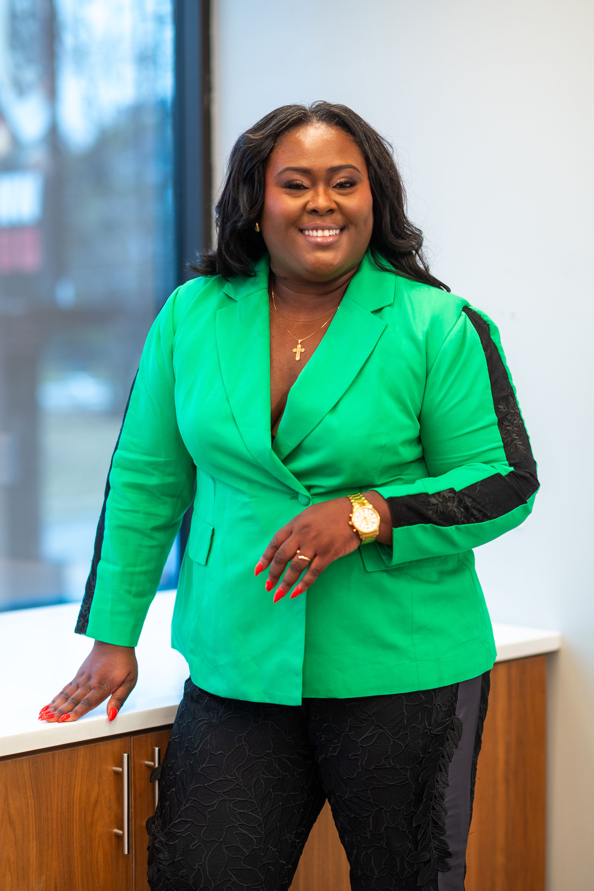 Ona Oghogho, founder of Adode Media, smiling and standing in a bright office